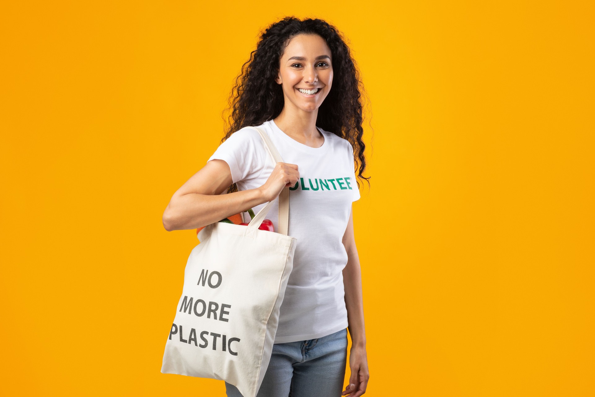 Volunteer Woman Carrying Eco Bag Standing In Studio, Yellow Background